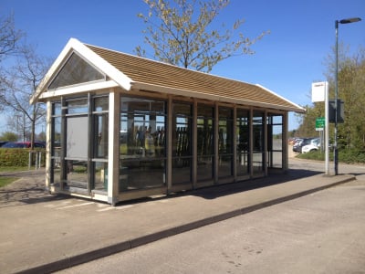 Bespoke park and ride waiting area bus shelter with timber wood frame and toughened glass glazing.